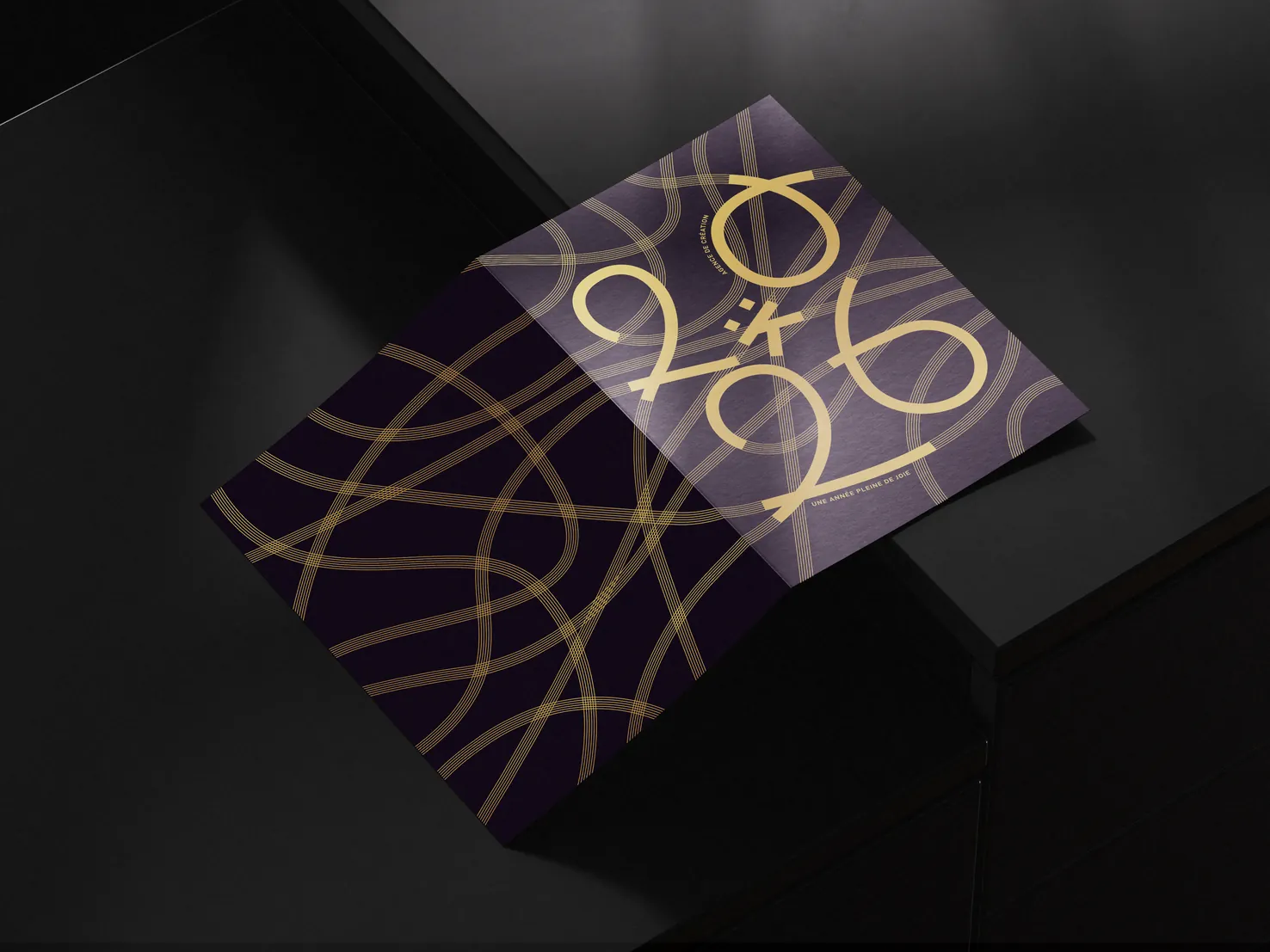 Carte de vœux Kinome 2026 posée à plat : lettrage doré entrelacé sur papier violet profond